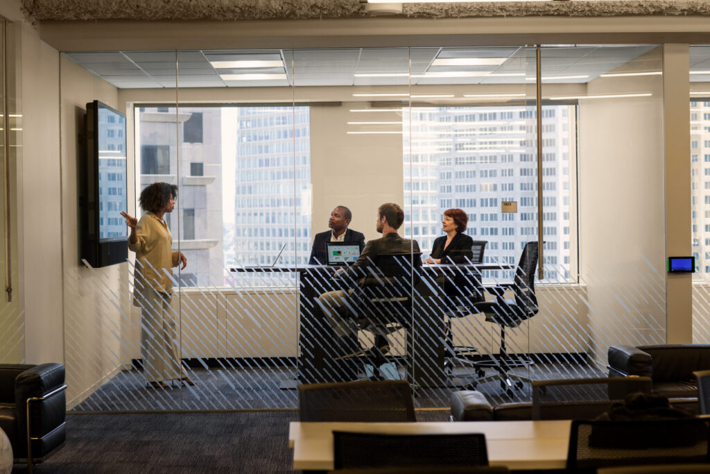 people sitting in the meeting room, one person is presenting standing next to the whiteboard