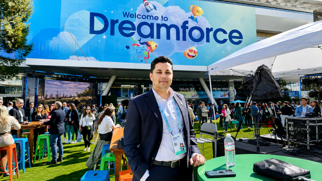 A man in front of a Dreamforce welcome sign