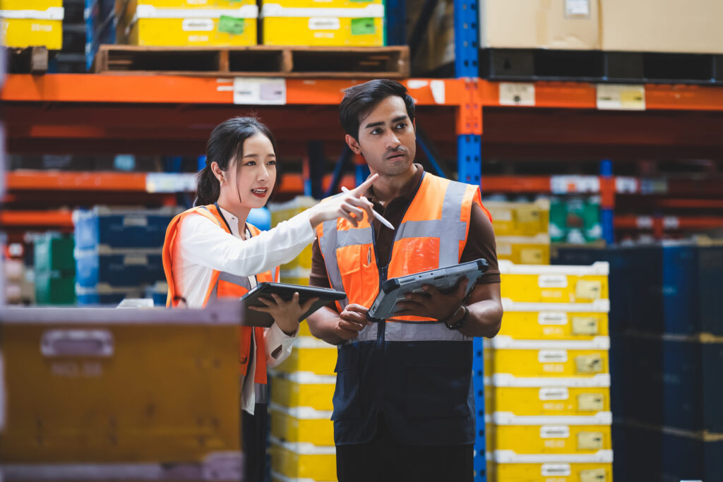 Warehouse worker and manager checks stock and inventory with using digital tablet computer in the retail warehouse full of shelves with goods. Working in logistics, Distribution center